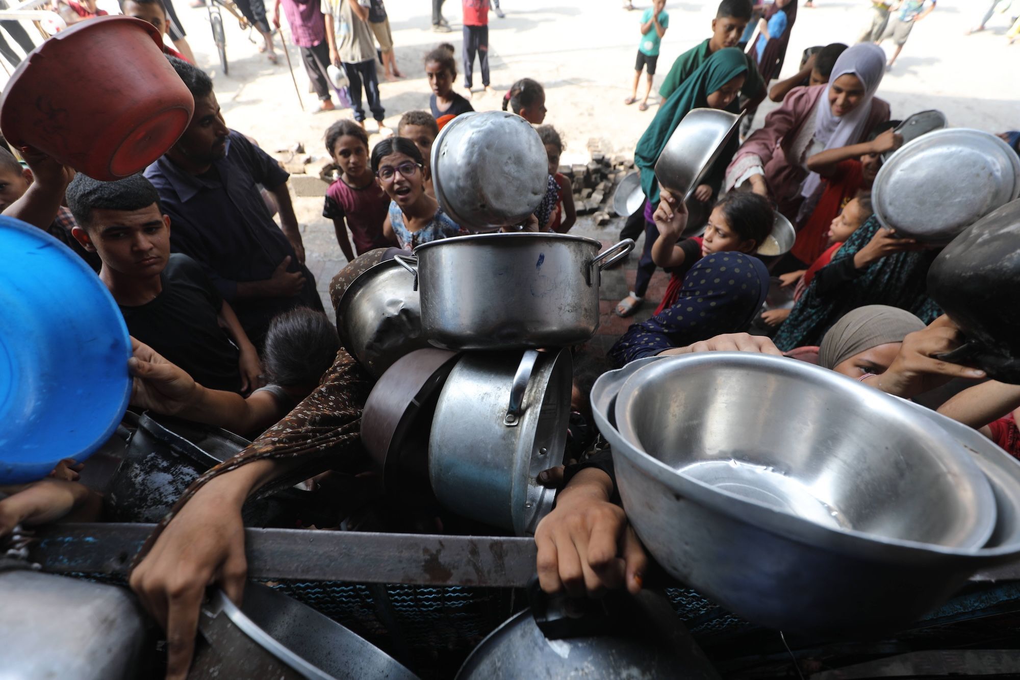 Menschen in Gaza stehen in einer Schlange für Lebensmittel mit leeren Töpfen an